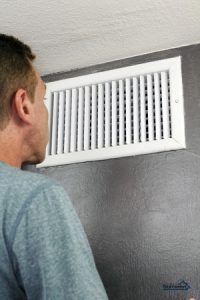 man standing in front of an AC vent
