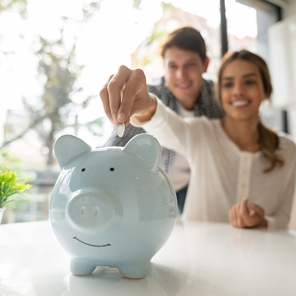 young couple saving coins into piggy bank