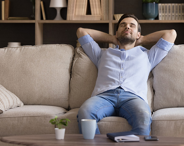 Peaceful millennial man relaxing on couch