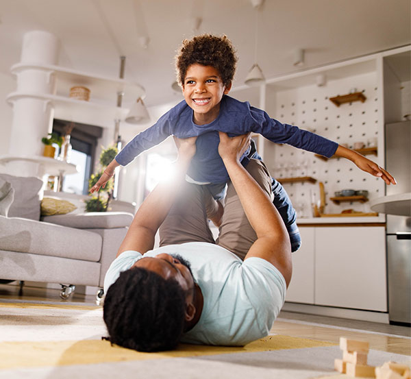 Father and boy having fun while playing on floor in the living room.